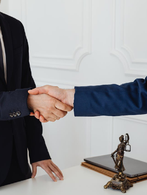 Lawyer and client shaking hands in front of a statue, symbolizing partnership and collaboration at a law firm.