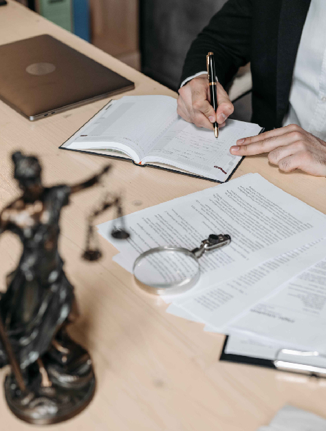 Lawyer in a suit seated at a desk, working on a laptop surrounded by legal documents and papers, providing legal help.