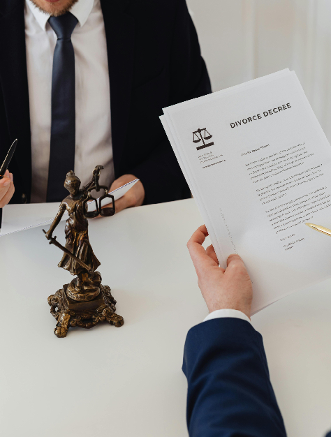 A lawyer and client in suits discussing divorce matters, holding legal documents and a statue of justice for emphasis.